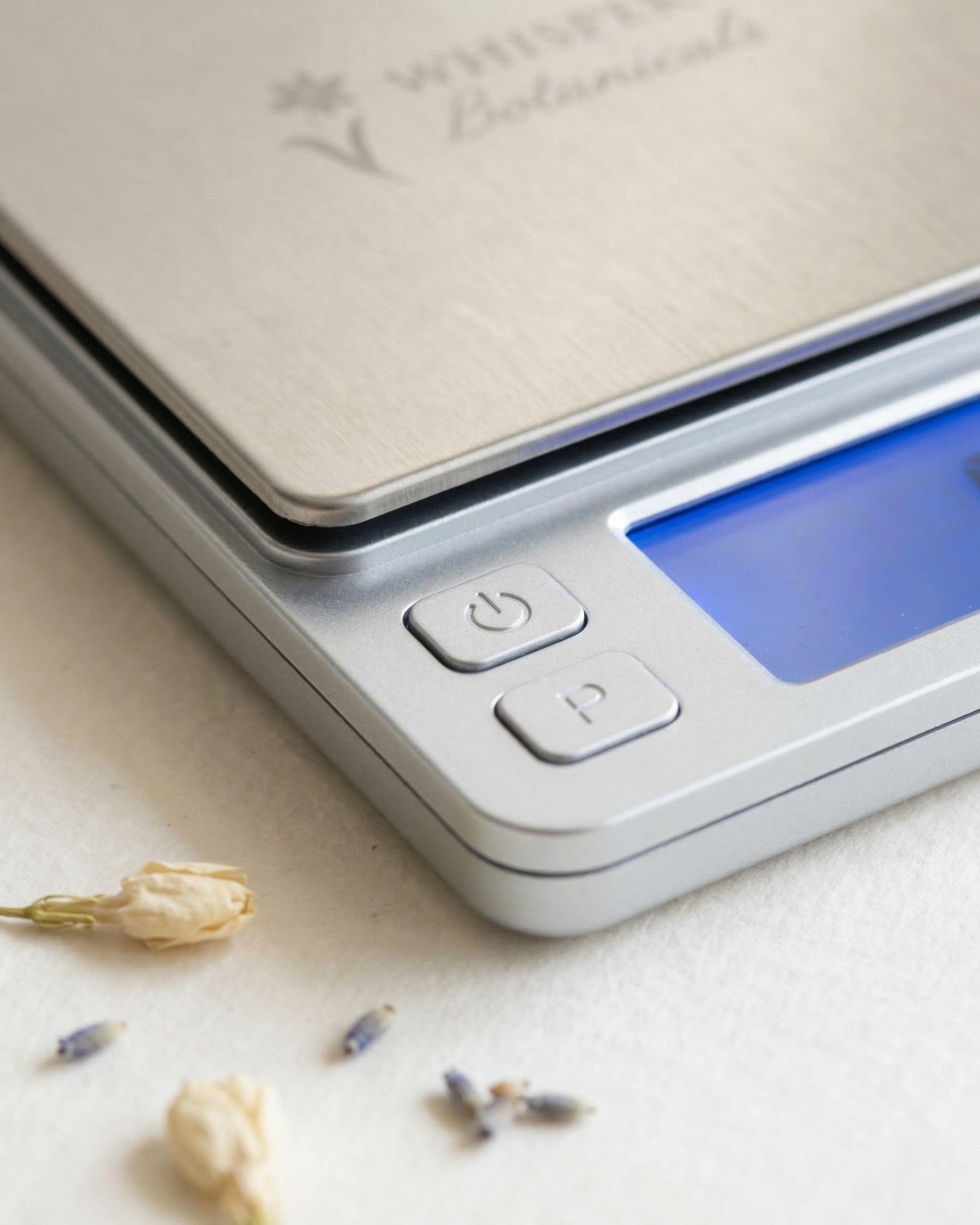 Digital kitchen scale on a light surface with small flowers around.